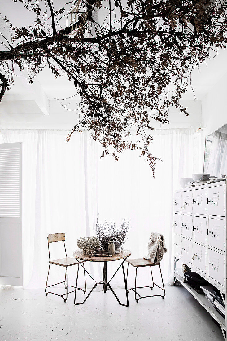 Weißes Esszimmer mit Vintage-Möbeln und Baum-Ast als Dekoration