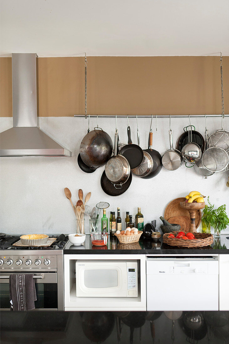 Pans hung on wall above kitchen counter, gas cooker and extractor hood