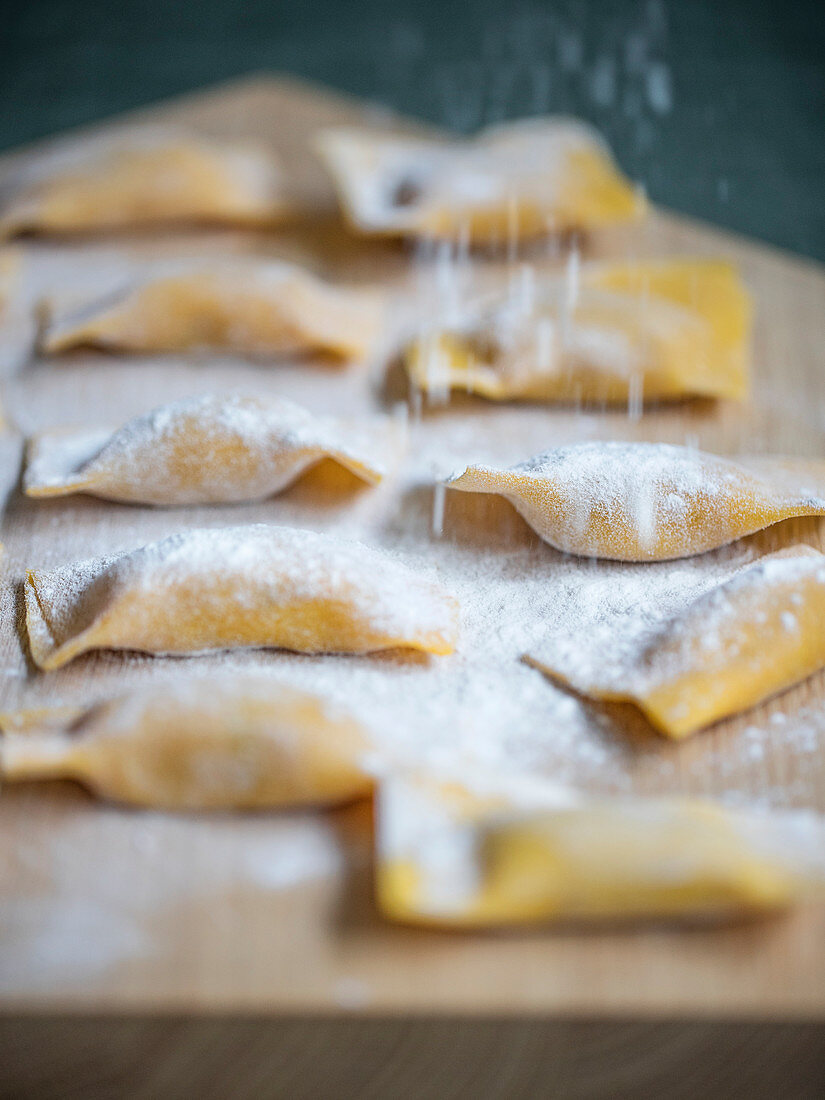 Tortelli di zucca (Kürbis-Nudeltaschen, Italien) mit Mehl bestauben