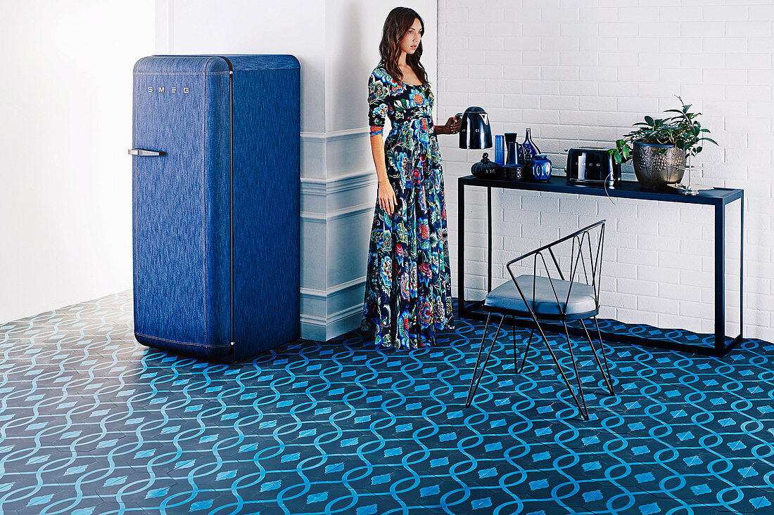 Blue tiled floor with organic pattern and blue fridge, woman at console