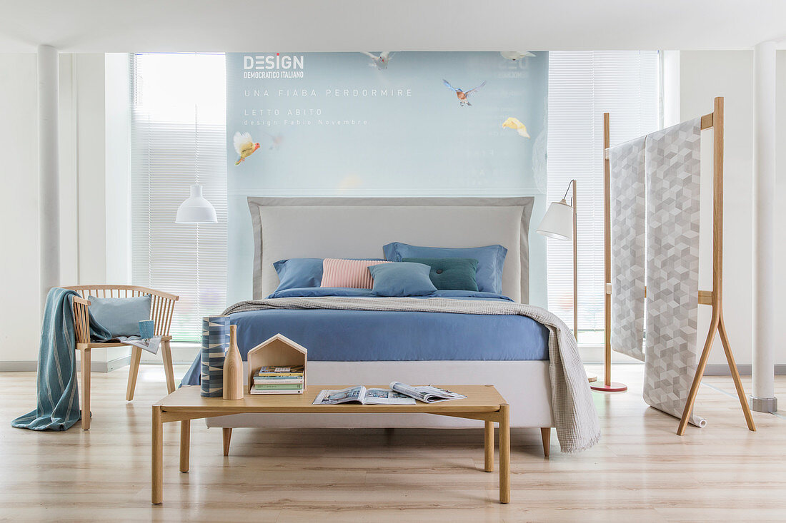 White double bed with headboard and pastel-blue bed linen in open-plan bedroom with partition wall