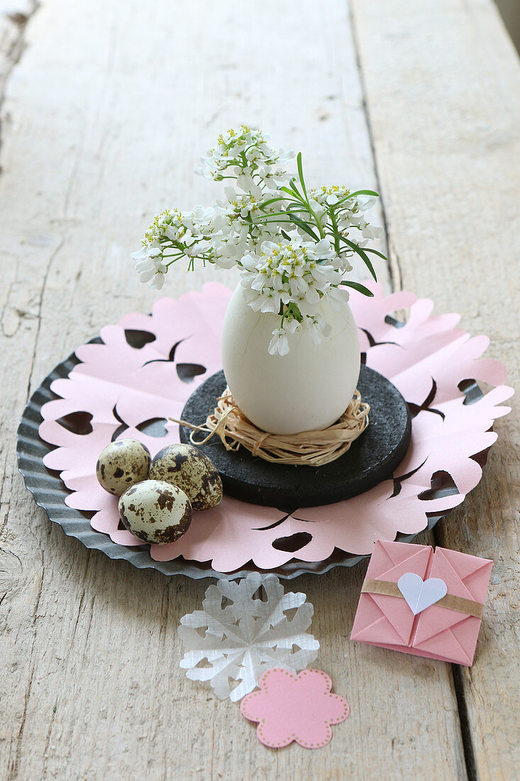 Osterdekoration mit Entenei als Vase mit kleinen weissen Blumen und handgemachtem Briefumschlag