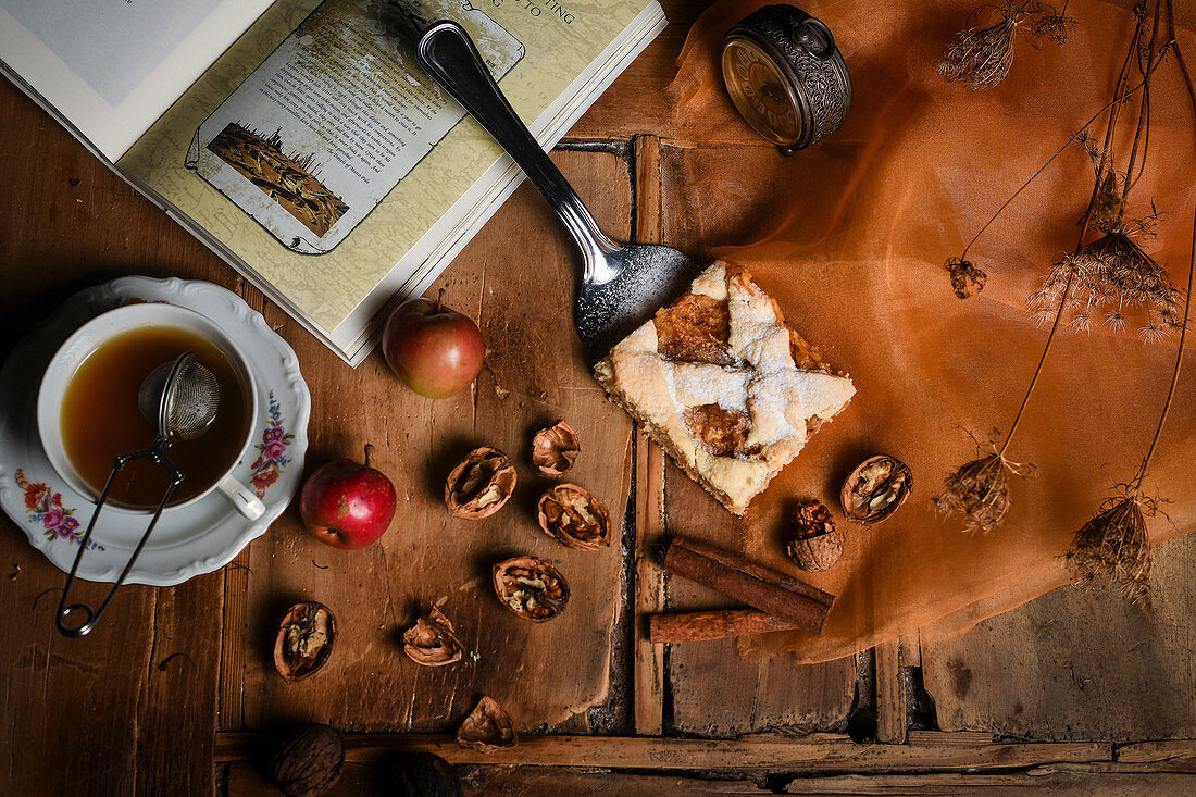 A piece of apple pie tray bake with cinnamon and nuts, served with a cup of tea