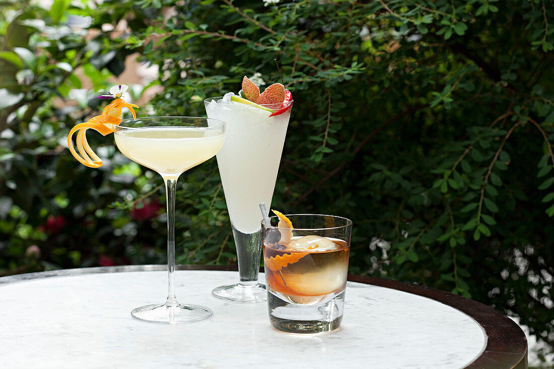 Drei verschiedene Cocktails auf Gartentisch