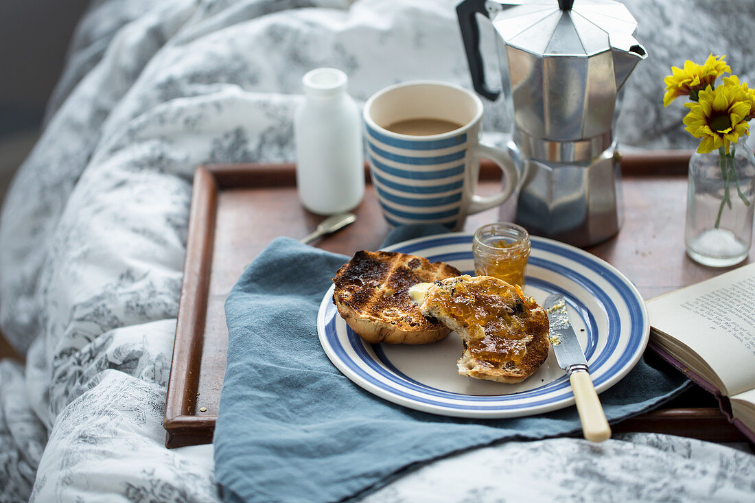 Breakfast in bed with coffee, a toasted scone, and jam