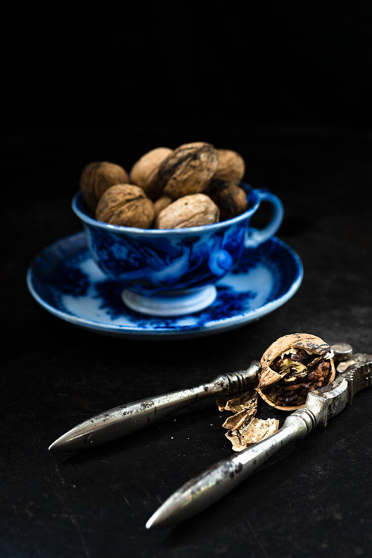 Walnuts in a cup next to a nutcracker