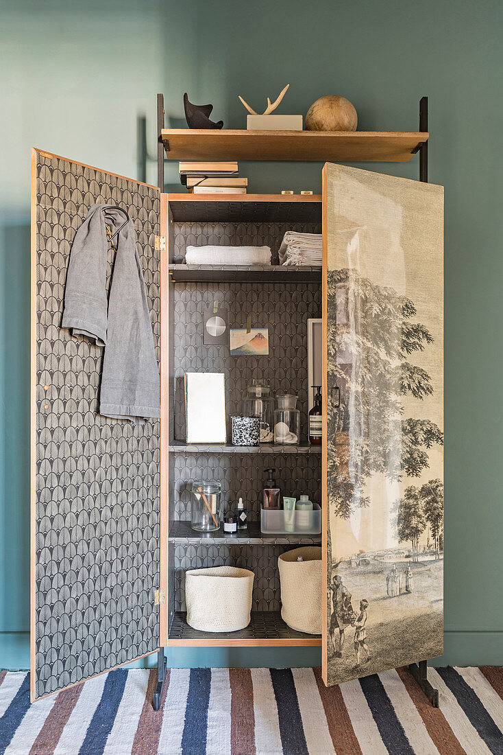 Bathroom utensils in old, refurbished wardrobe covered with vintage-style wallpaper