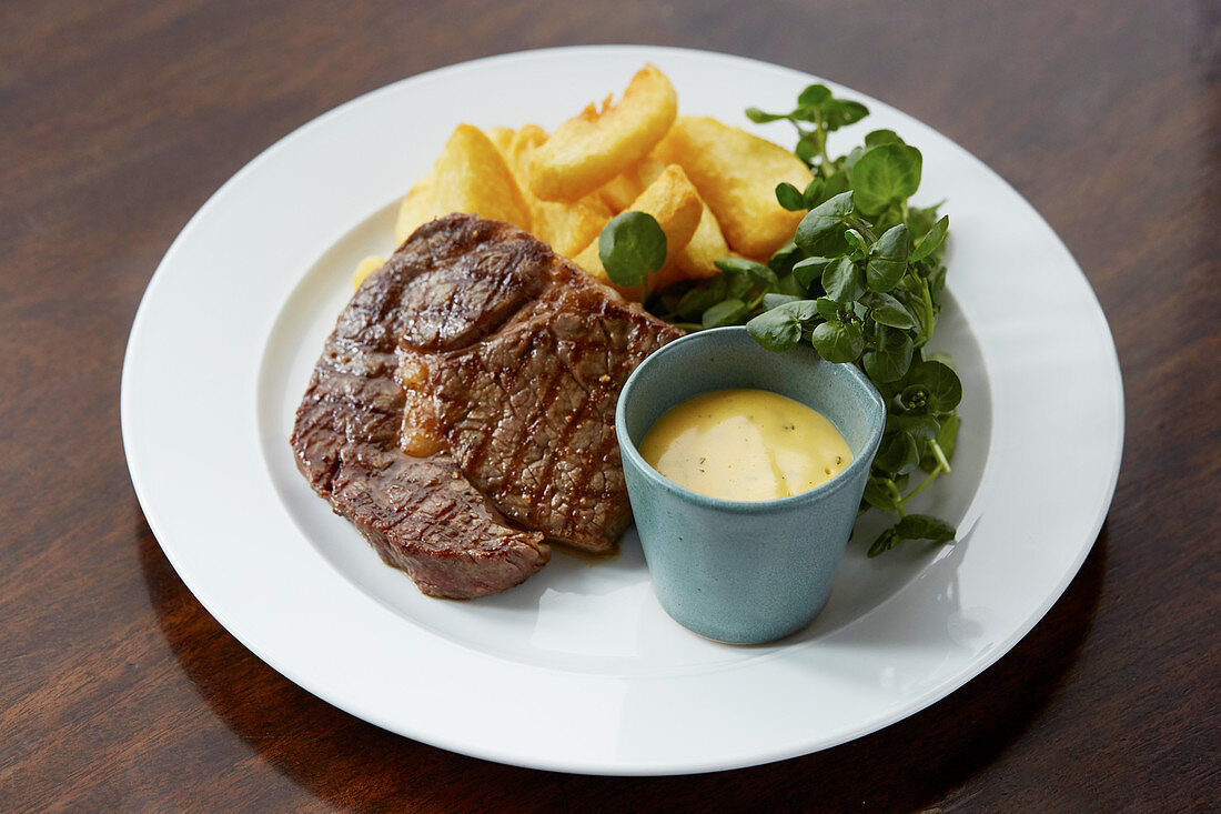 Steak and chips with hollandaise sauce served on the side