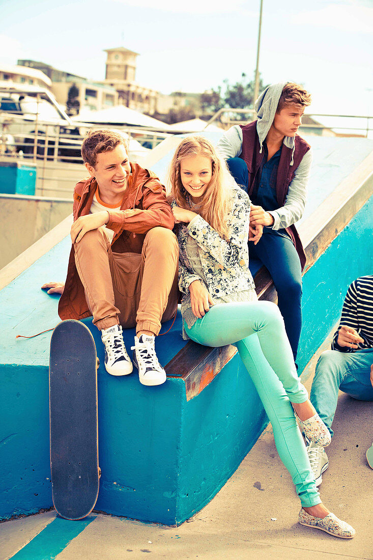 A group of young people wearing fashionable clothing relaxing with skateboards