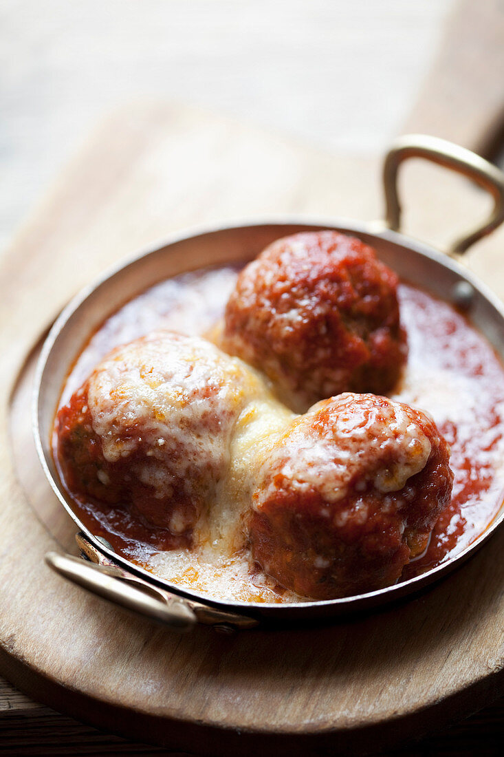 Meatballs in a tomato sauce topped with cheese
