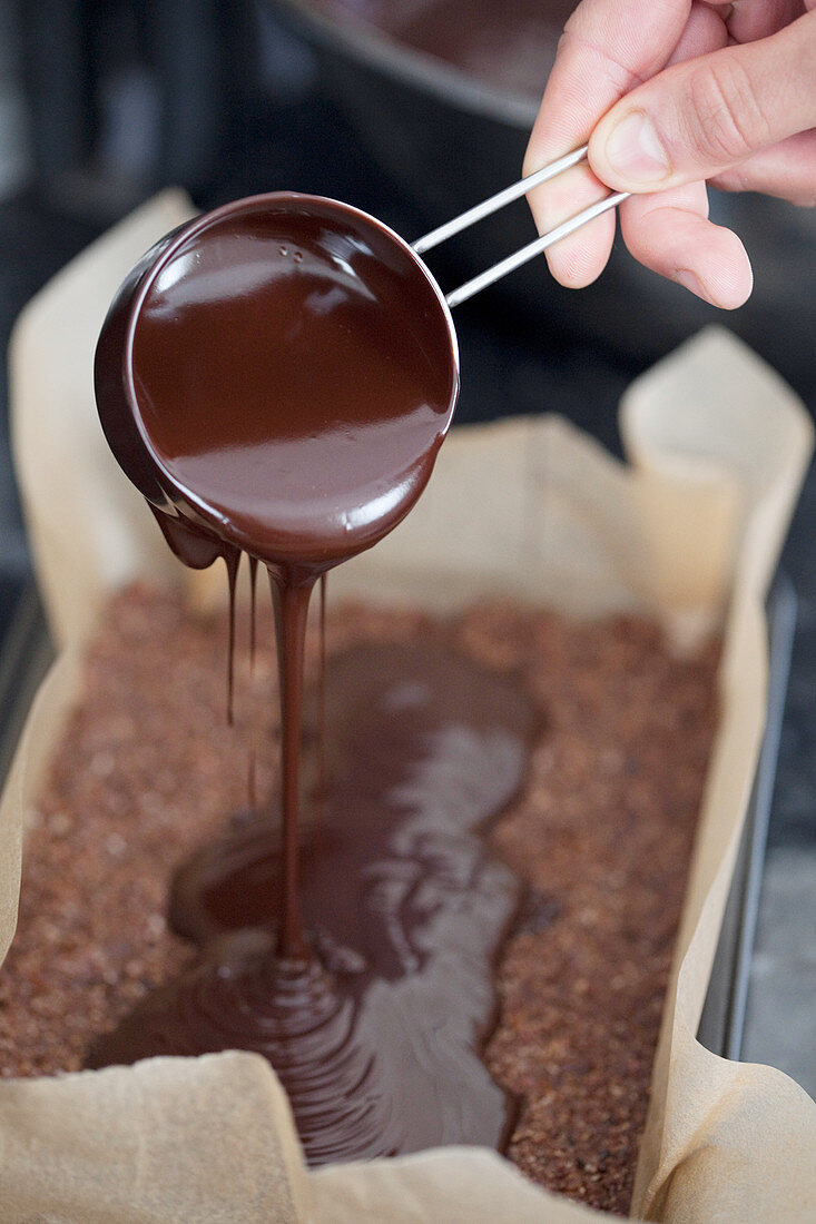 Geschmolzene Schokolade auf Biskuitkuchen gießen