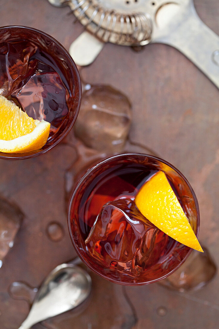 Two old fashioned cocktails in cut glasses with mixing equiptment