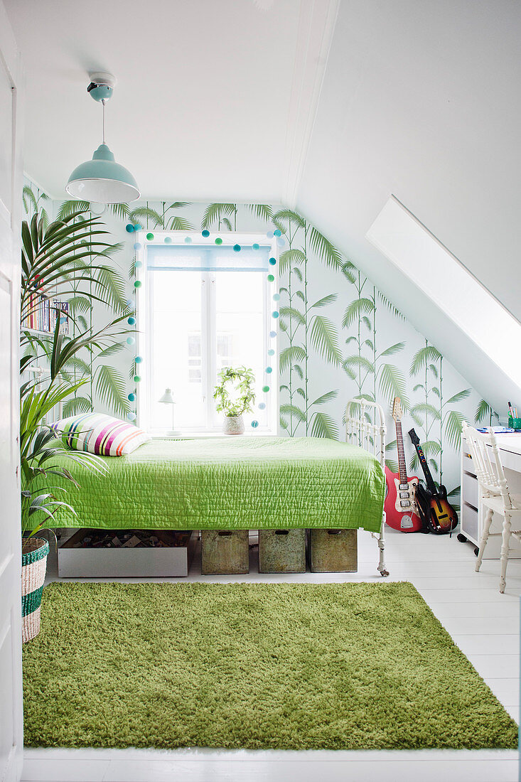 White-and-green bedroom with sloping ceiling and jungle-patterned wallpaper
