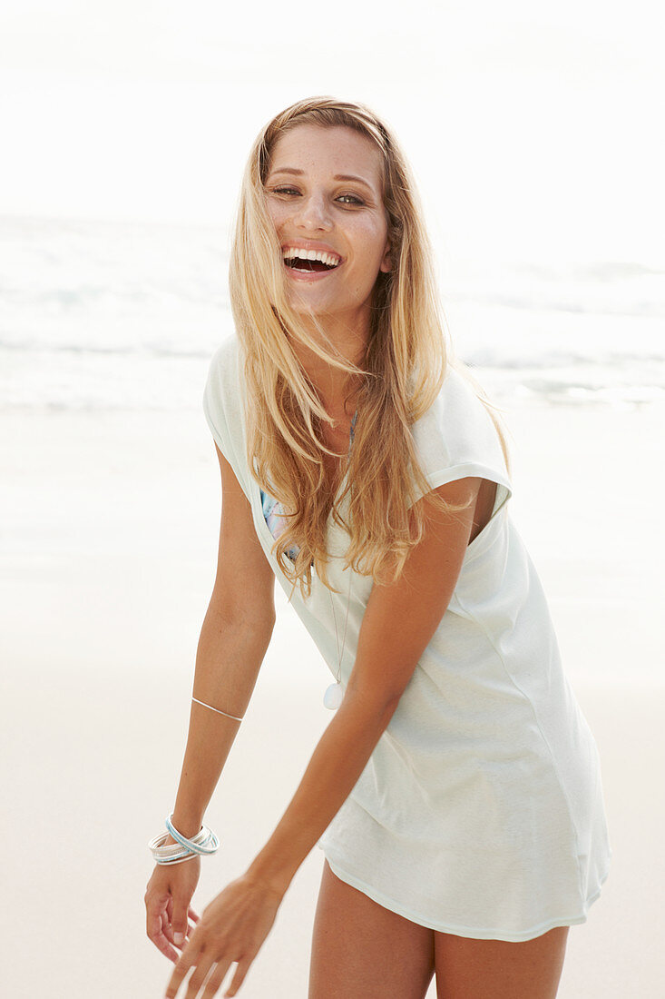 A blonde woman on a beach wearing a long top