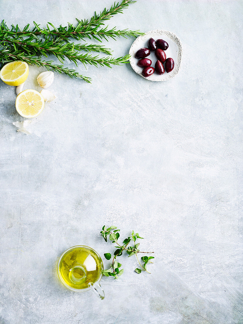 Kräuter, Oliven, Zitronen, Knoblauch und Olivenöl auf weißem Untergrund