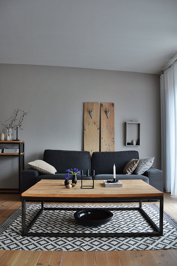 Living room in shades of grey: couch in front of wooden panel and coffee table on rug