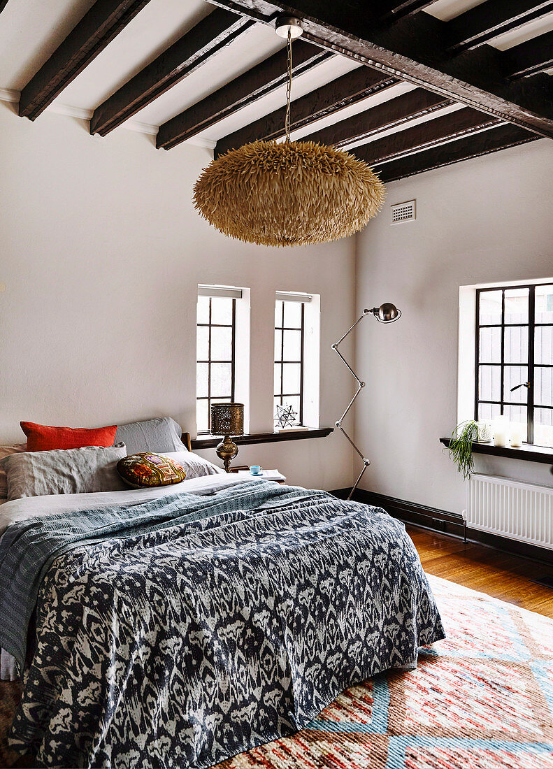 Double bed with bedspread, Moroccan lamp in the bedroom with dark beams