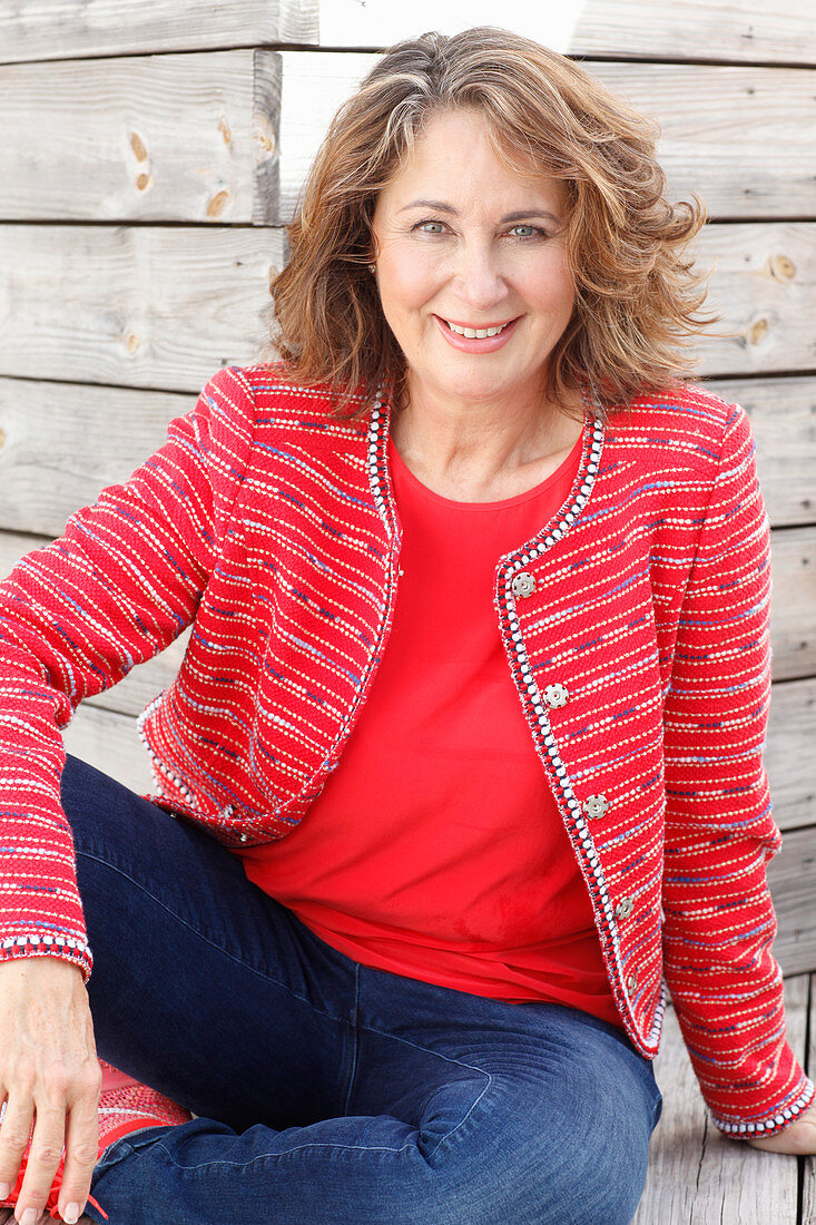 Brünette Frau in rotem Top, roter Jacke und Jeans