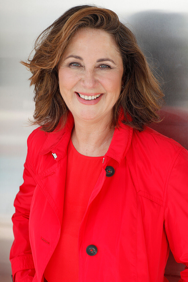 A brunette woman wearing a red top and a red trench coat