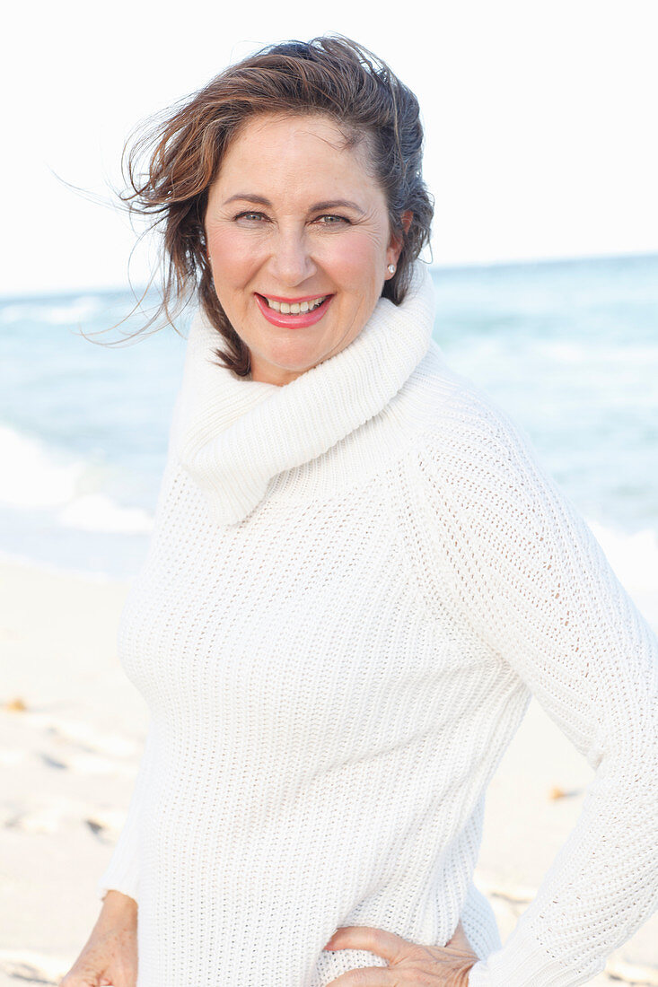 Brünette Frau in weißem Strickpullover am Strand