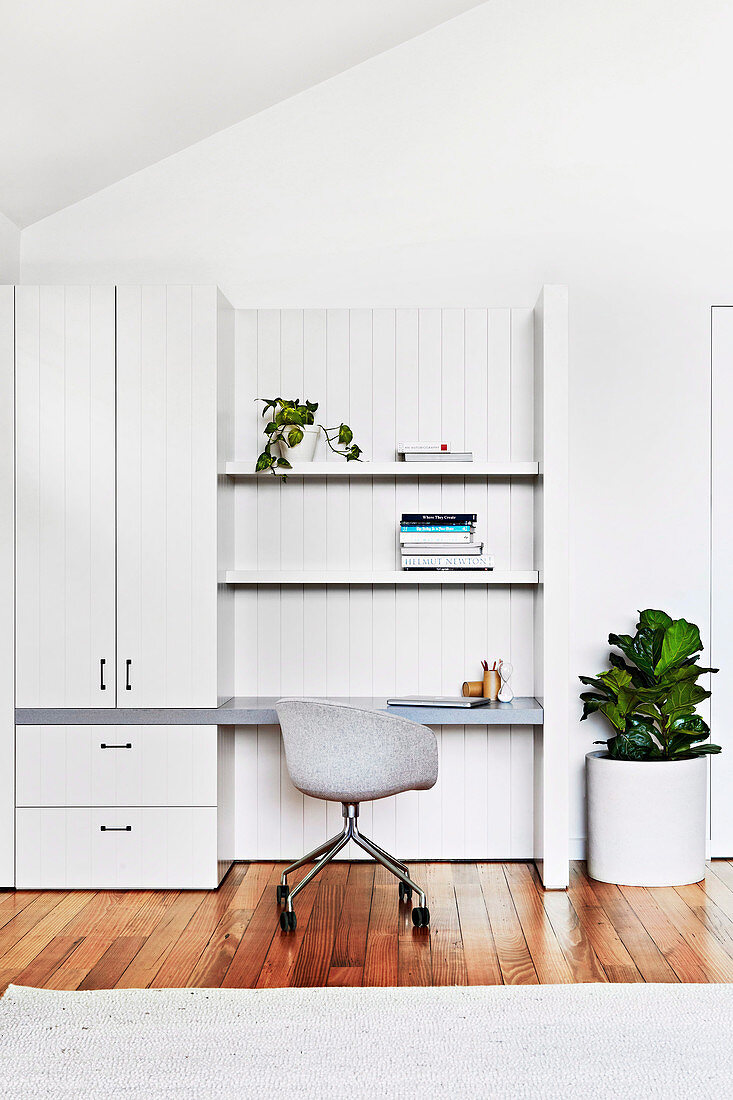 White cupboard and shelf with integrated desk, shell chair in front