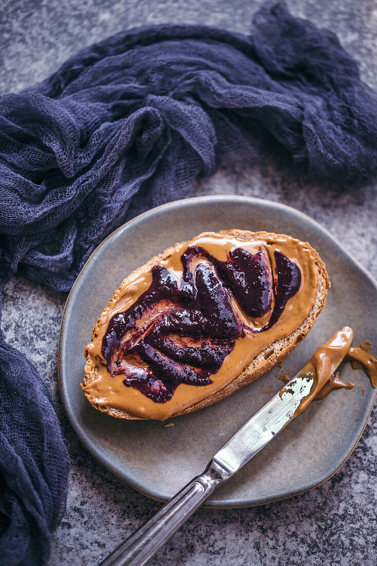 Brotscheibe mit Erdnussbutter und Blaubeermarmelade