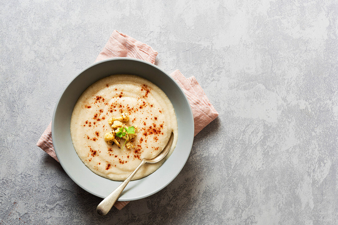 A bowl of roasted cauliflower soup with a spoon
