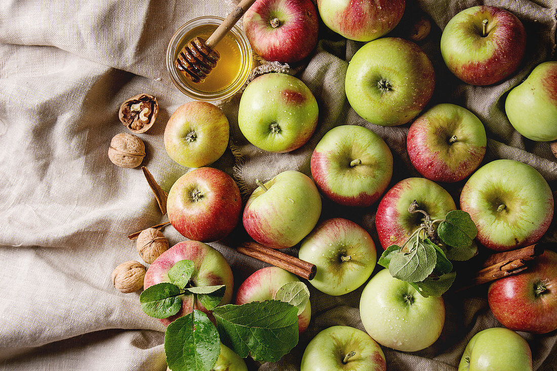 Ripe organic gardening green red apples with leaves, walnuts, cinnamon and jar of honey