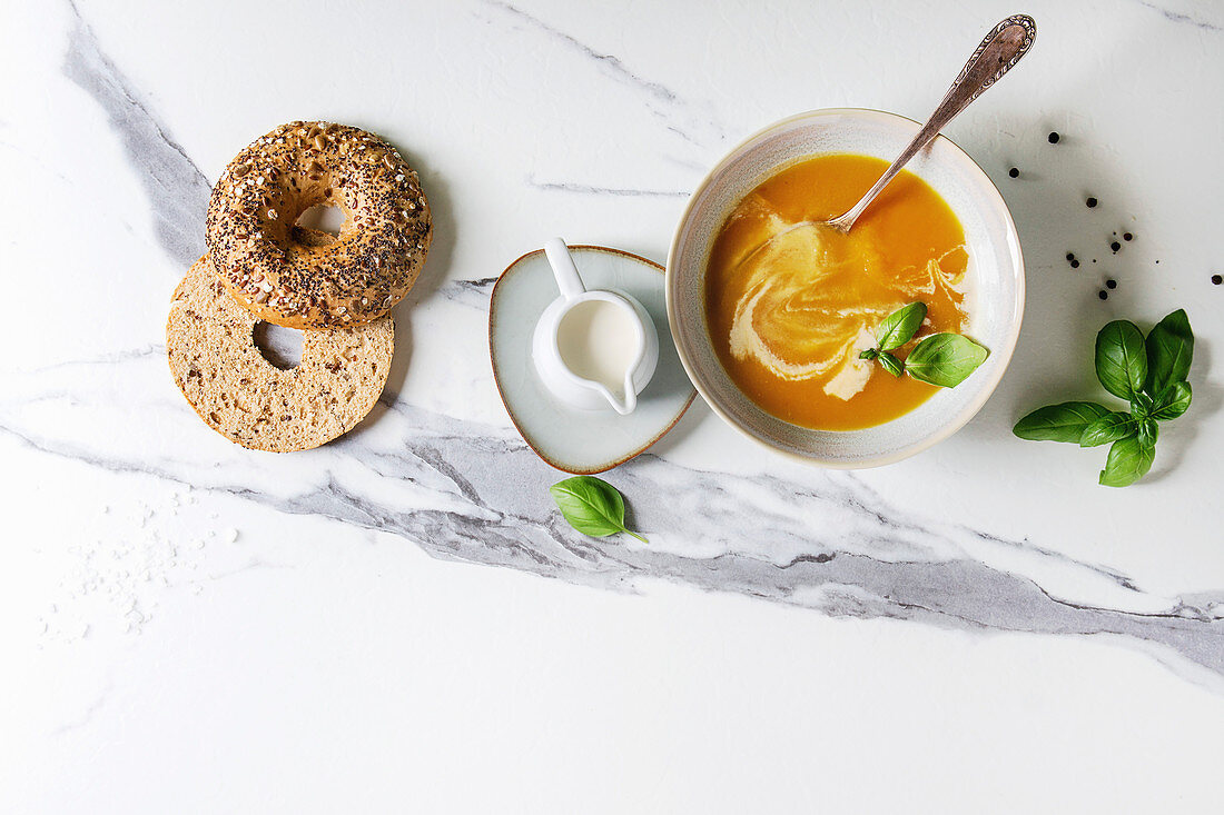 Vegetarische Karotten-Kürbissuppe serviert in Schale mit Mehrkorn-Bagel (Aufsicht)