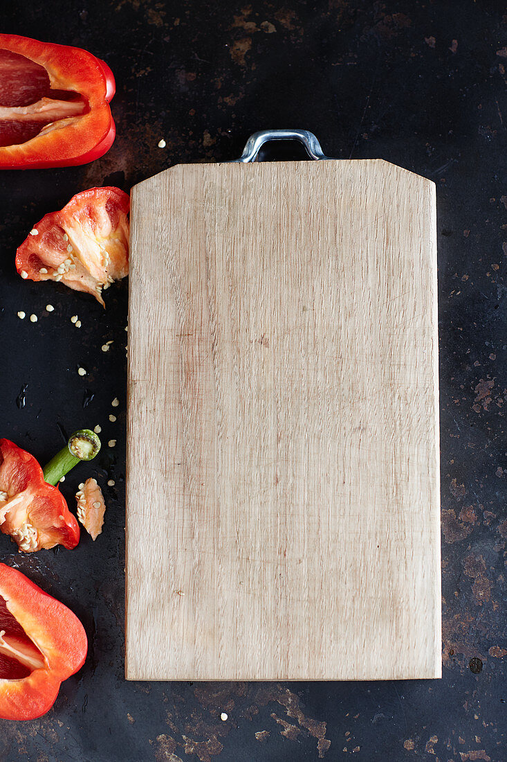 A wooden chopping board and red peppers