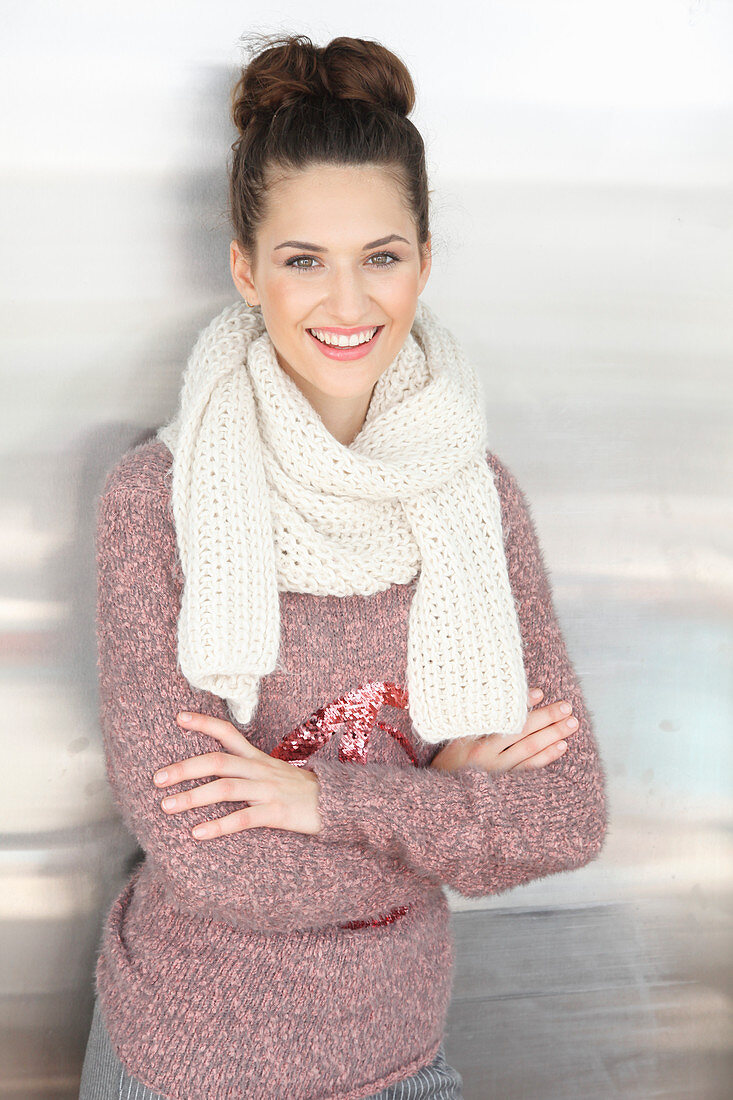 A brunette woman wearing a white scarf with a mottled pink-grey knitted jumper