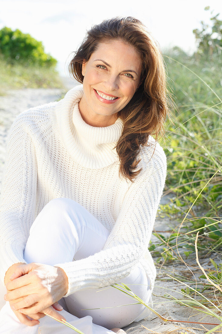 Brunette woman wearing white knit sweater and white trousers