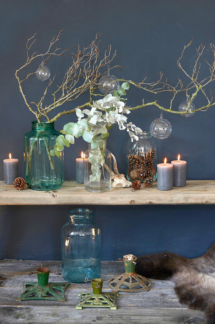 Arrangement of natural items in blue and green on wooden shelves on blue wall