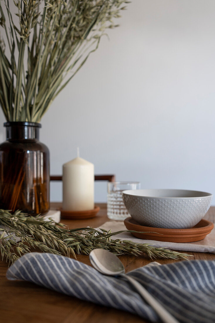 Table set with candle and ears of cereal in apothecary bottle