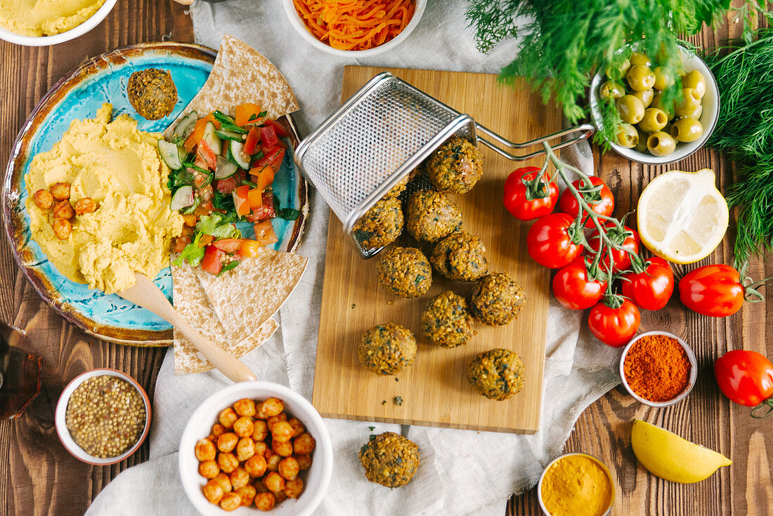 Fried falafel balls on wooden board surrounded with different ingredients