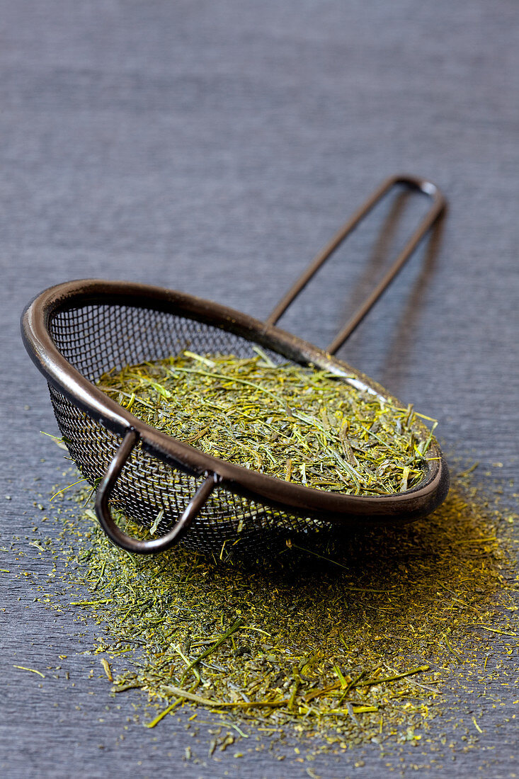 Japanese green tea leaves in a metal strainer