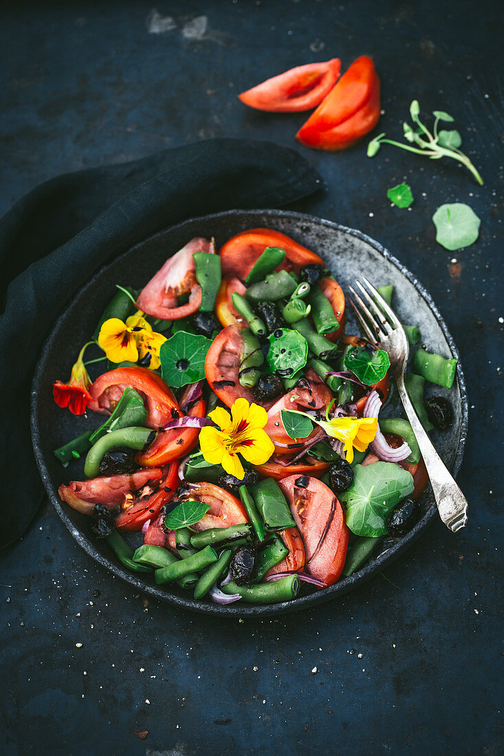 Tomato and bean salad with flowers in a grey bowl