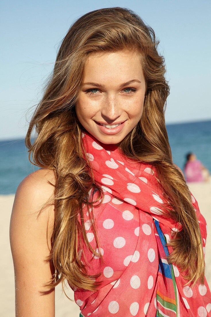 A young blonde woman by the sea wearing a beach towel