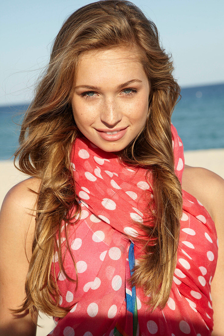 A young blonde woman by the sea wearing a beach towel