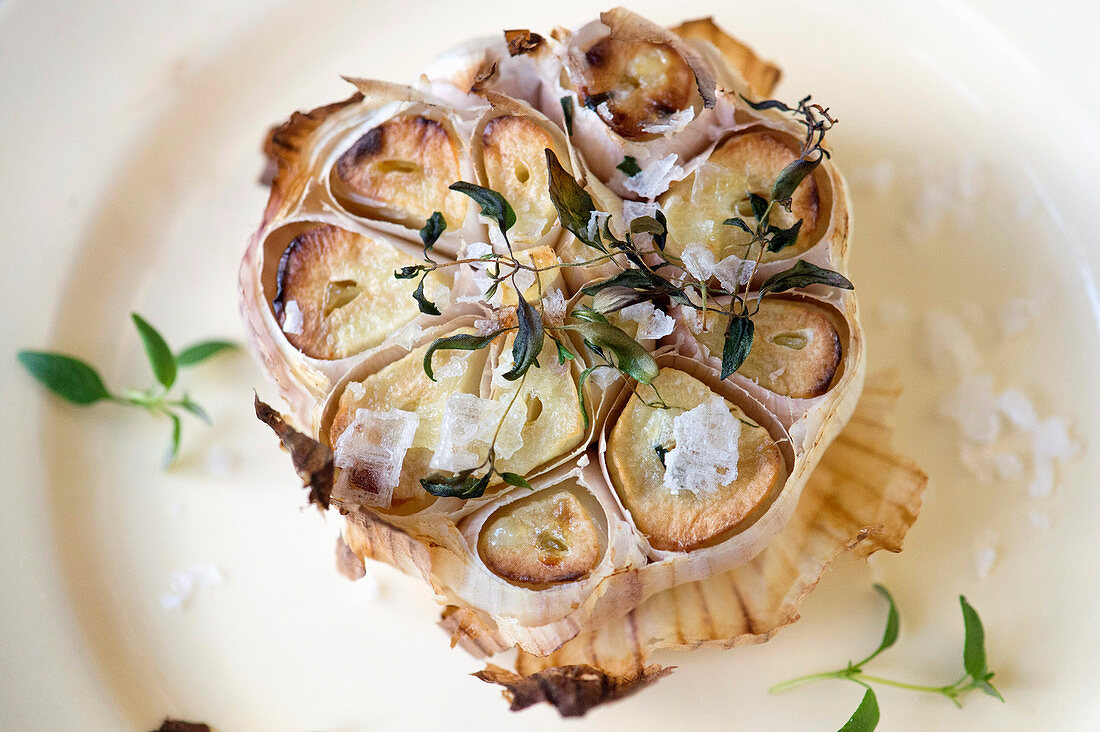 Ofengebackener Knoblauch mit Kräutern und Salzflocken (Nahaufnahme)