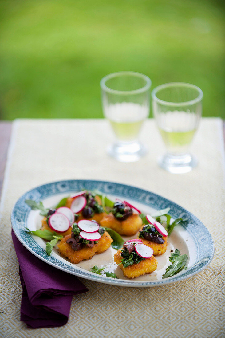 Crispy polenta canapés with rocket, olives and radishes