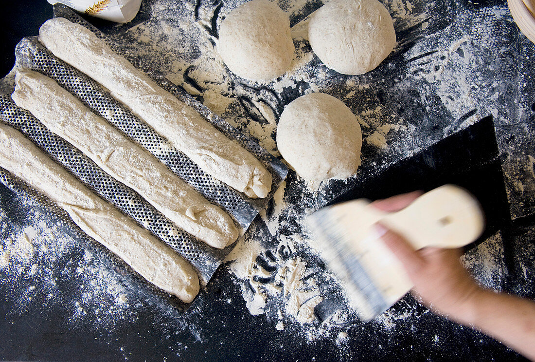 Unbaked rolls and baguettes on a floured work surface