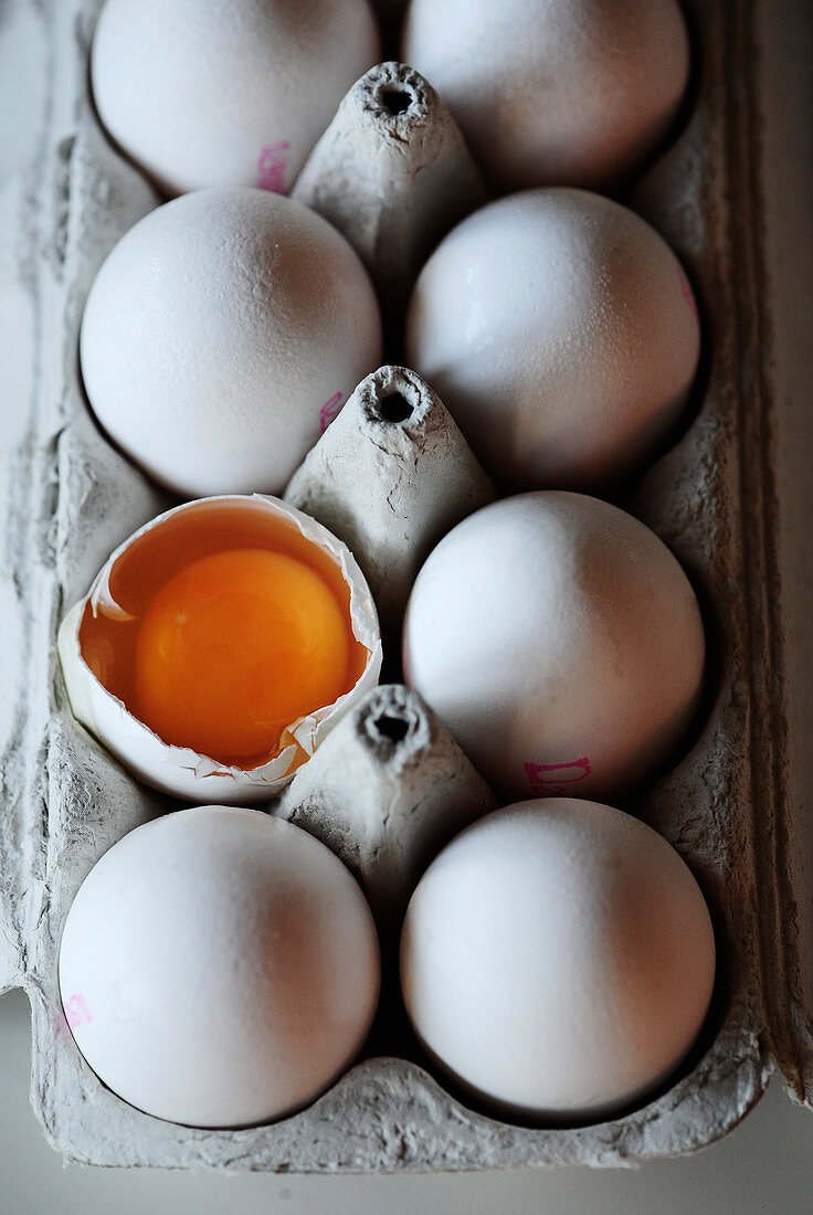 Eier, ganz und aufgeschlagen, im Eierkarton