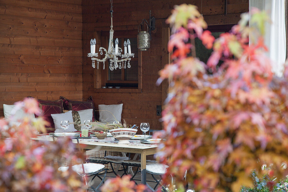 Gedeckter Tisch, darüber Kronleuchter in herbstlichem Ambiente