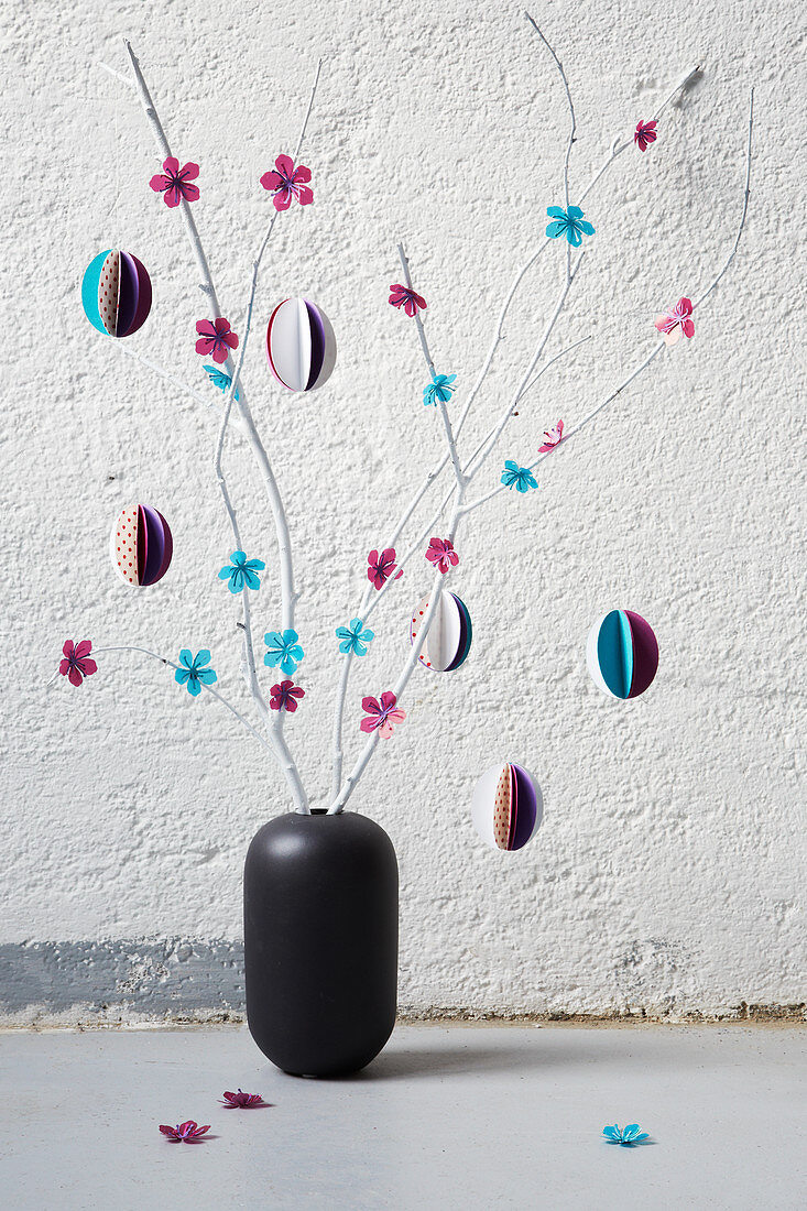 Vase of branches decorated with paper flowers and paper Easter eggs