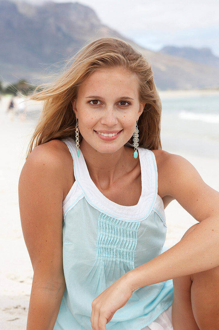 Junge blonde Frau im hellblauen Top am Strand