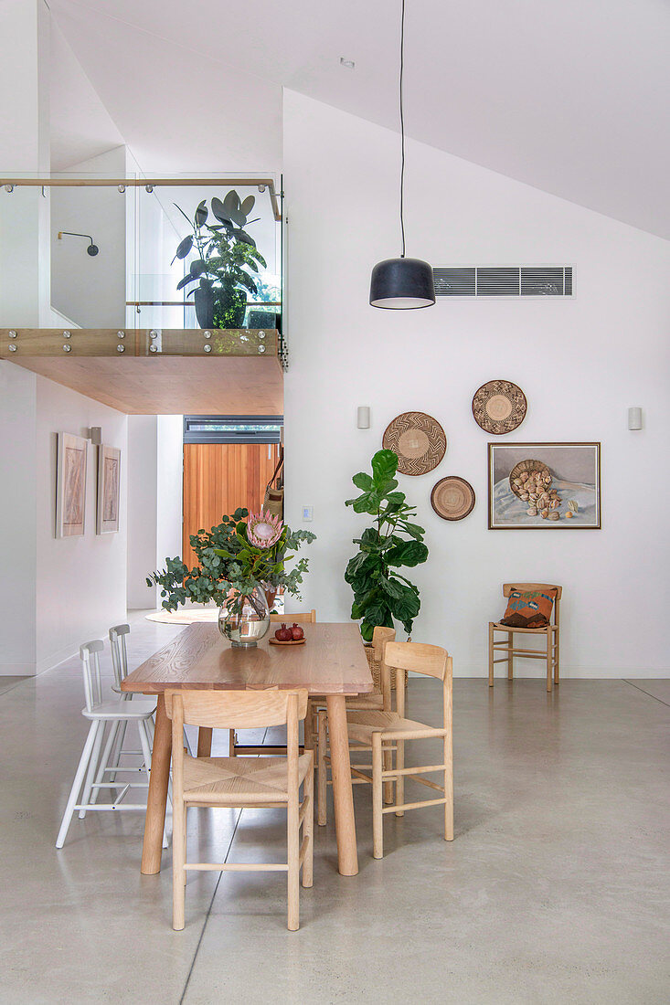 Dining table in the open-plan living room with concrete floor and gallery