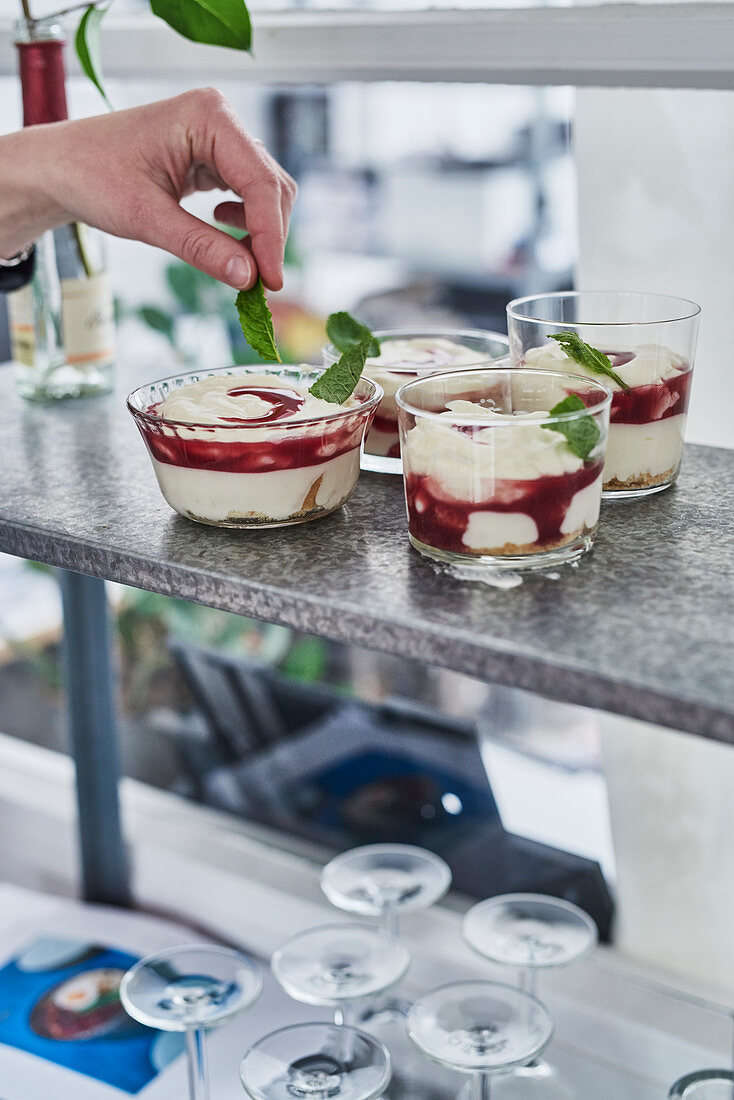 Cheesecakes in glasses being garnished with mint
