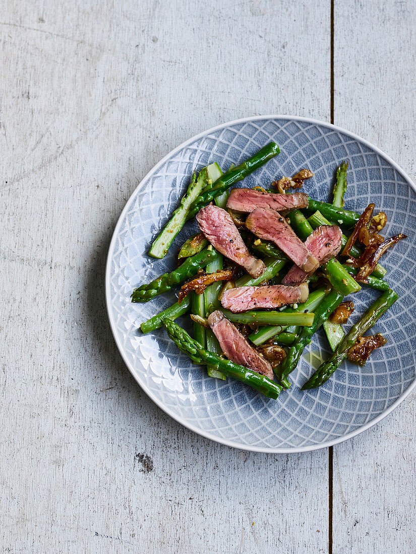 Marinated beef strips on green asparagus and dates