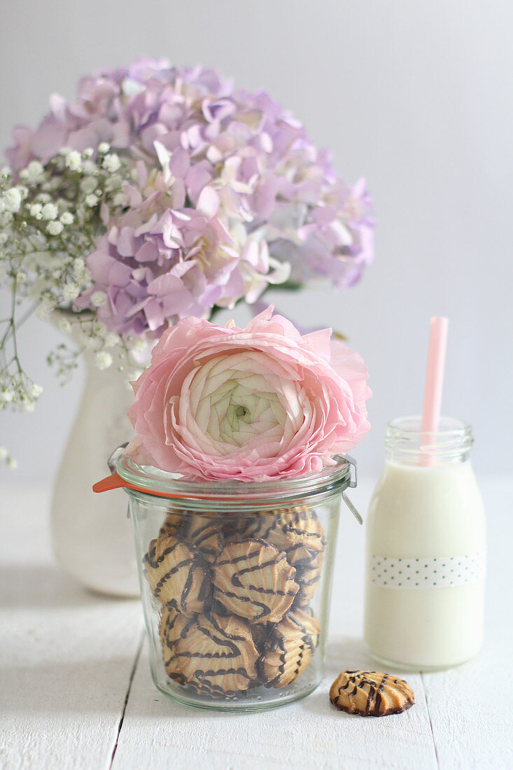 Plätzchen mit Schokoladenglasur im Einmachglas dekoriert mit Rosenblüte